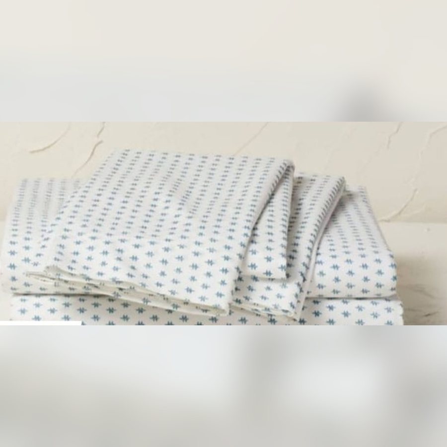 Folded white sheet set with a small teal print